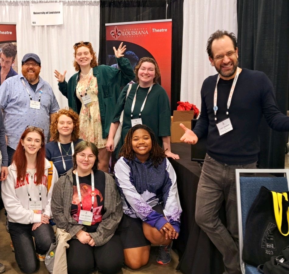 A group photo taken at the University of Louisiana at Lafayette's booth at The South Eastern Theatre Conference. Laurel is pictured in the back with her hands up.
